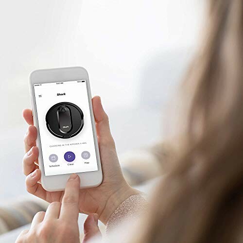 Person using smartphone app to control robot vacuum.